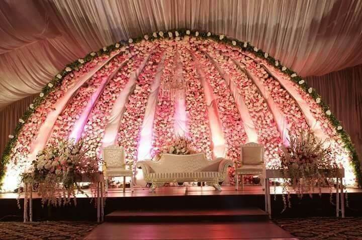 Royal wedding reception stage with floral dome backdrop, pastel flowers and elegant seating arrangement