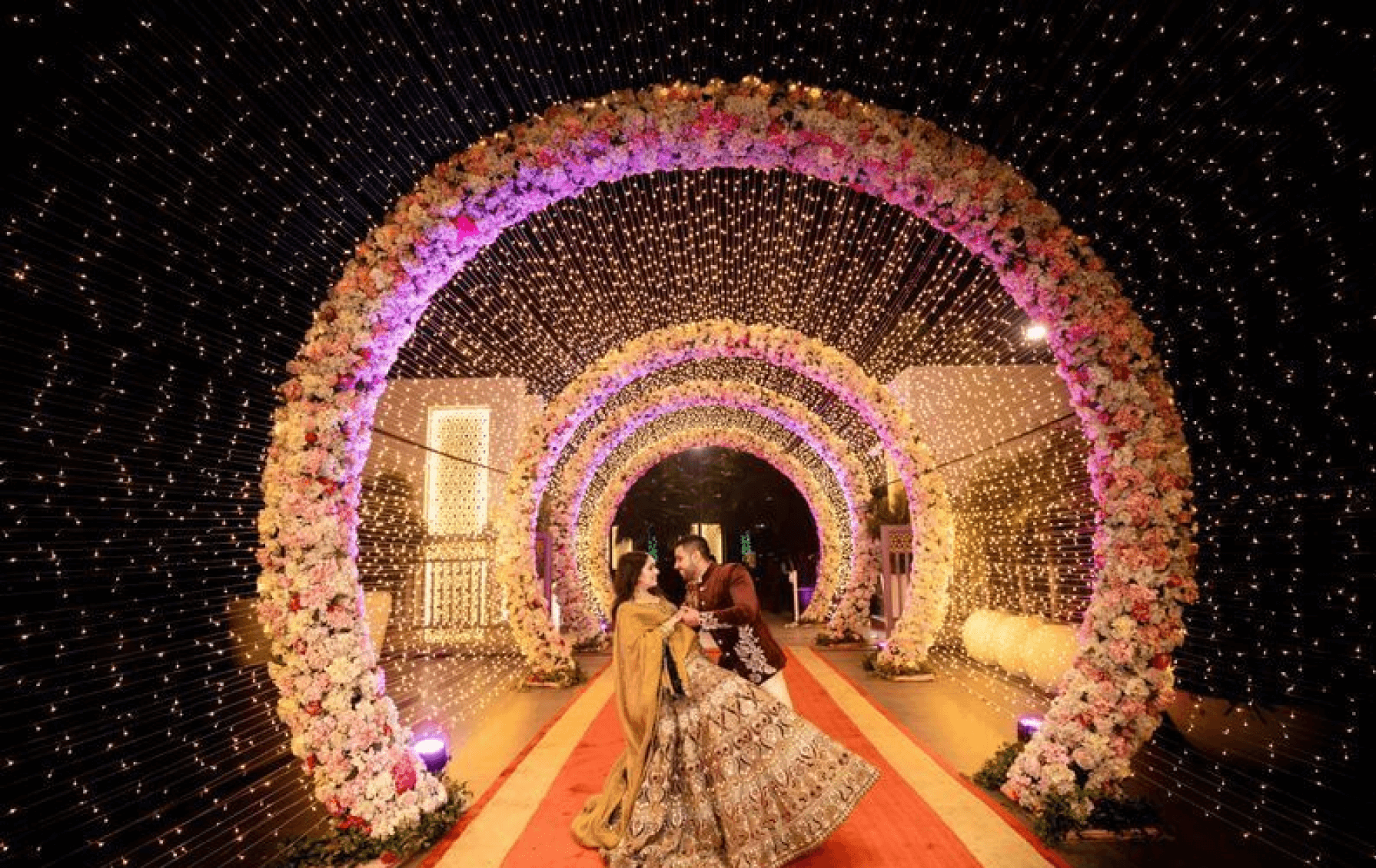 Luxury wedding reception entry with floral arches, fairy lights tunnel and romantic couple moment