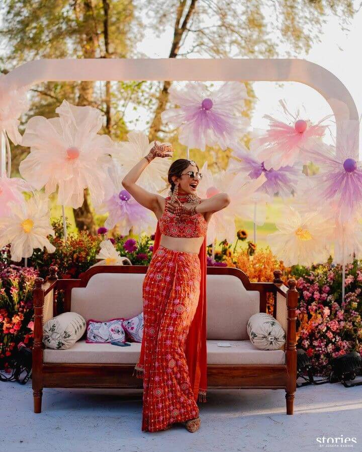 Bride dancing at Indian wedding mehndi ceremony with floral decoration.